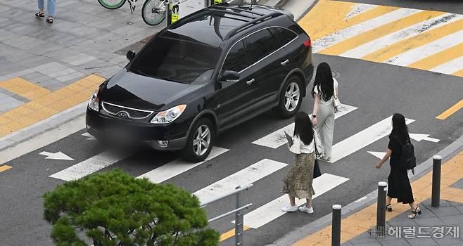 횡단보도 앞 일시정지 의무 확대 내용이 담긴 도로교통법 개정안 시행일인 12일 서울 용산구의 한 교차로에서 시민들이 횡단보도를 건너는 도중 한 차량이 행인을 무시한 채 횡단보도를 지나고 있다. 임세준 기자