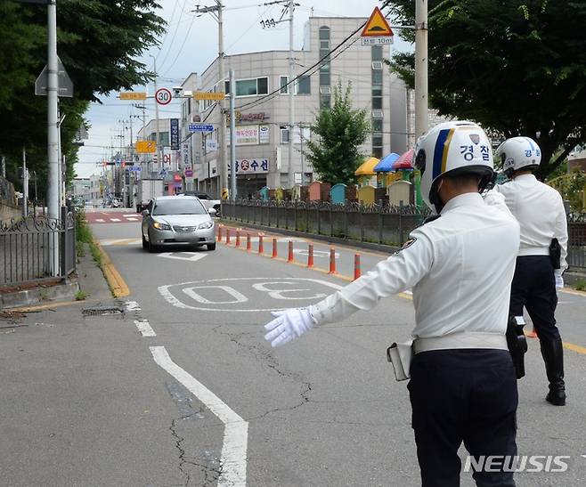 [청주=뉴시스] 조성현 기자 =  횡단보도 앞 일시정지 등 보행자 보호 의무를 강화한 도로교통법 개정안 시행 첫날인 12일 충북 청주시 상당구 용암동 인근 도로에서 경찰들이 계도 활동에 나서고 있다. 개정된 도로교통법에 따르면 모든 운전자는 횡단보도에 보행자가 통행하고 있는 경우뿐만 아니라 '통행하려고 하는 때'에도 일시 정지해야 한다. 어린이 보호구역 내의 신호 없는 횡단보도에서는 보행자의 통행 여부와 관계없이 멈춰야 한다. 이를 위반하는 경우 승용차 기준 범칙금 6만원과 10점의 벌점이 부과된다. 2022.07.12. jsh0128@newsis.com