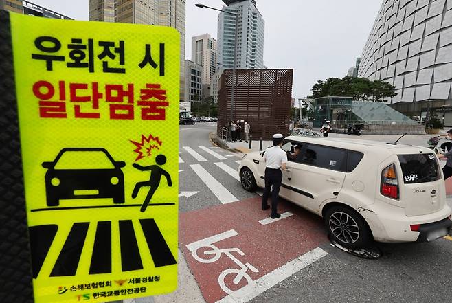 '횡단보도 보행자 보호'를 골자로 하는 개정 도로교통법 시행 첫날인 7월12일 서울 송파구 잠실역 교차로에서 송파경찰서 경찰관들이 계도 활동을 하고 있다. ⓒ 연합뉴스