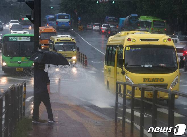 수도권에 호우주의보가 내려진 13일 서울 서대문구 연세대학교 앞에서 한 시민이 차량이 만드는 물보라를 피하고 있다.  2022.7.13./뉴스1 © News1 신웅수 기자