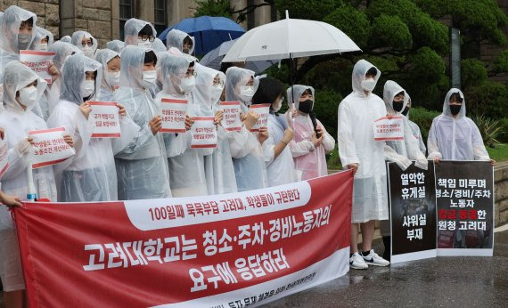 13일 서울 성북구 고려대학교 본관 앞에서 열린 고려대 청소·주차·경비노동자 문제해결을 촉구하는 학생 기자회견에서 학생과 노동자들이 손팻말을 들고 있다. 연합뉴스