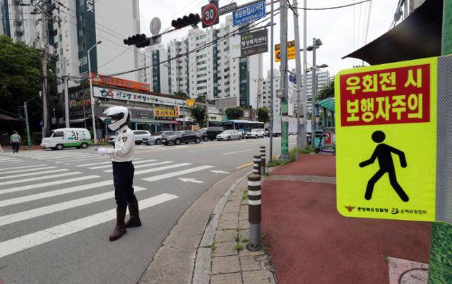 횡단보도 앞 '일시정지' 의무를 확대하는 개정 도로교통법 시행 첫날인 12일 충북 청주 시내 도로에서 교통경찰관이 운전자 주의를 당부하는 형태로 계도 활동을 하고 있다. 연합뉴스