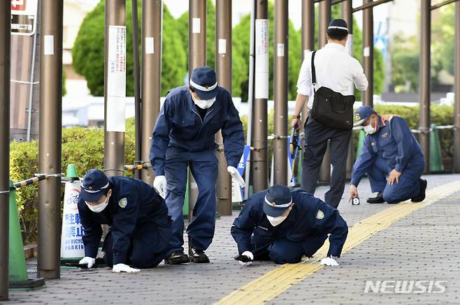 [나라=AP/뉴시스] 일본 경찰이 13일 일본 서부 나라현에서 아베 신조 전 일본 총리가 총격으로 쓰러진 현장 인근 보도를 조사하고 있다. 2022.07.13