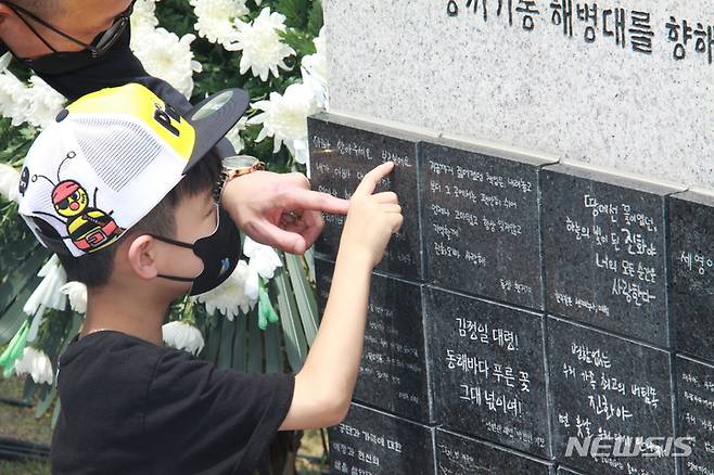 [포항=뉴시스] 이바름 기자 = 17일 오전 경북 포항특정경비지역사령부 내 마린온 순직자 위령탑에서 마린온 순직자 4주기 추모행사가 열린 가운데, 고 노동환 중령의 아들이 자신이 적은 비석을 가리키고 있다. 2022.07.17. right@newsis.com