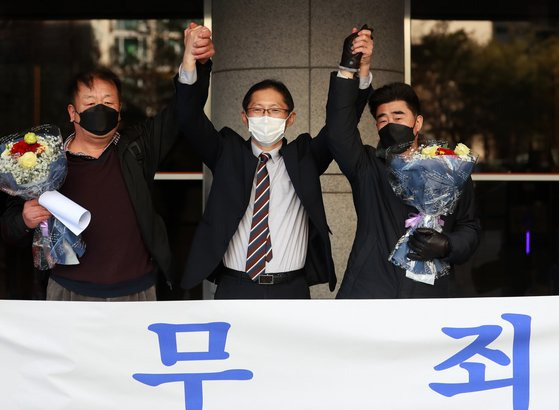 경찰 고문에 못 이겨 살인죄 누명을 쓴 채 21년간 억울한 옥살이를 한 '낙동강변 살인사건' 피해 당사자 최인철(왼쪽)씨와 장동익씨, 박준영 변호사(가운데)가 지난해 2월 부산고등법원에서 열린 재심 선고 공판을 마치고 손을 맞잡고 있다. 연합뉴스