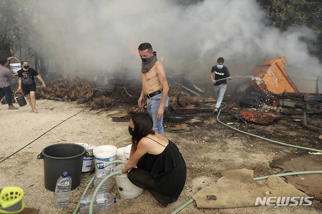 [레이리아=AP/뉴시스] 12일(현지시간) 포르투갈 중부 레이리아 외곽 피게이라스 마을에서 주민들이 주택으로 산불이 번지는 것을 막기 위해 화마와 싸우고 있다. 포르투갈에 계속된 폭염으로 전국에서 32건의 산불이 발생해 3000명 넘는 소방대원과 30대의 소방 항공기가 불길과 싸우고 있다. 2022.07.13.