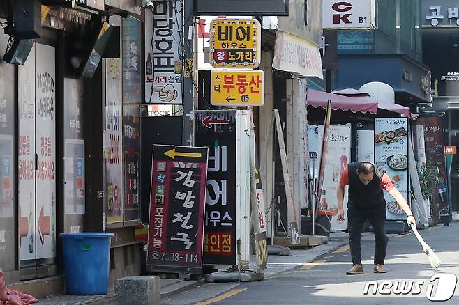 . 17일 서울 종로구 먹자골목에서 한 업주가 가게 앞을 청소하고 있다. 2022.4.17/뉴스1 © News1 민경석 기자