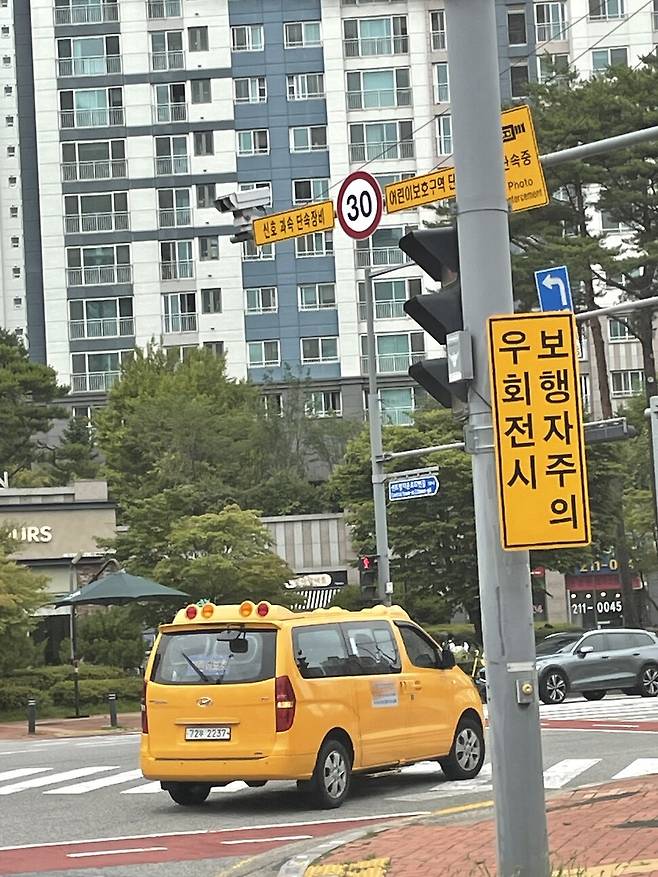 지난 18일 오후 경기도 수원 광교 새도시 한 교차로에서 어린이 통학버스가 우회전 시 보행자를 주의할 것을 알리는 표지판을 따라 조심스럽게 횡단보도를 지나고 있다.