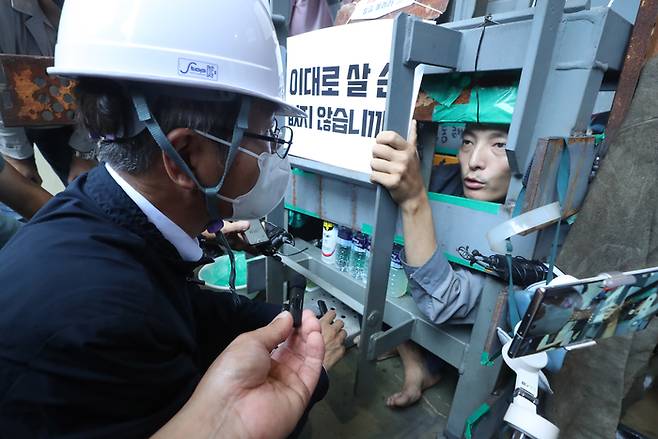 이정식 고용노동부 장관이 지난 19일 경남 거제시 아주동 대우조선해양 옥포조선소 파업 현장을 방문해 조선소 독 화물창 바닥에 가로, 세로, 높이 각 1ｍ 철 구조물 안에서 농성 중인 유최안 금속노조 거제통영고성 조선하청지회 부지회장과 면담하고 있다. 연합뉴스