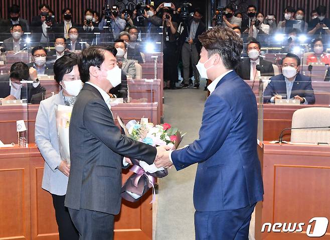 이준석 국민의힘 대표(오른쪽)가 14일 서울 여의도 국회에서 열린 의원총회에서 성남 분당갑 6·1 보궐선거에서 당선된 안철수 의원에게 꽃다발을 전달하고 있다. (공동취재) 2022.6.14/뉴스1 © News1 허경 기자