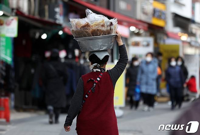 서울 중구 남대문시장에서 한 상인이 머리에 건어물을 얹은 채 판매하고 있다. 2022.2.22/뉴스1 © News1 조태형 기자