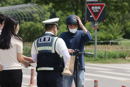 전동 킥보드 규정이 강화된 첫날인 지난해 5월13일 오후 서울 영등포구 여의도 한강공원에서 영등포경찰서 교통과 소속 경찰이 전동킥보드 관련 단속 및 계도를 하고 있다. [이미지출처=연합뉴스]