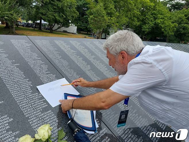 한국전 전사자 유가족으로 보이는 한 남성이 26일(현지시간) 미국 워싱턴DC 한국전 참전용사 기념공원내에 건립된 '추모의 벽'에 새겨진 잊혀진 영웅의 이름에 대해 탁본을 뜨고 있다.2020.7.27/뉴스1