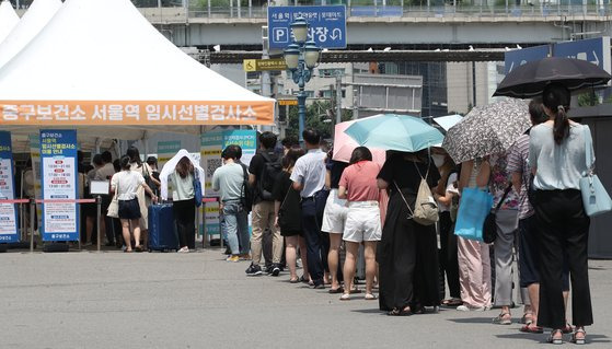 26일 서울 중구 서울역 신종 코로나바이러스(코로나19) 임시선별검사소에서 시민들이 검사를 위해 길게 줄을 서고 있다. 질병관리청 중앙방역대책본부는 이날 0시 기준 코로나19 신규 확진자가 9만9327명이라고 밝혔다. 1주 전(19일·7만3582명)보다 1.3배 많은 수치다. 뉴스1