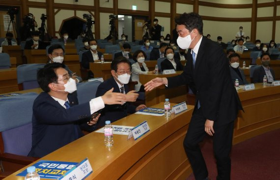 29일 오전 국회 의원회관에서 열린 더불어민주당 국민통합 정치교체 추진위원회 당대표 후보자 초청 공개토론회에 참석하기 위해 들어 온 강훈식 후보가 먼저 자리를 잡고 있는 박용진 후보에게 인사하고 있다. 박 후보 왼쪽은 이재명 후보. (공동취재) 뉴스1