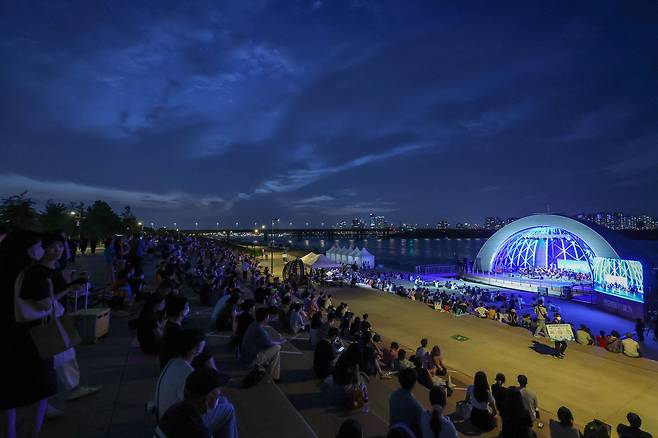 29일 오후 서울 여의도 물빛무대 인근 한강공원이 '한강 썸머 뮤직 피크닉' 공연을 관람하는 시민들로 붐비고 있다. 우상조 기자