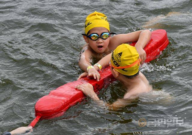 31일 서울 송파구 잠실 한강공원 수중보 일대에서 열린 제18회 서울특별시 철인3종협회장기 아쿠아슬론대회에서 지친 참가자들이 관계자의 안전부표를 붙들고 있다.