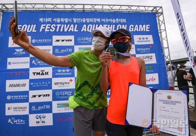 31일 서울 송파구 잠실 한강공원 수중보 일대에서 열린 제18회 서울특별시 철인3종협회장기 아쿠아슬론대회에서 완주한 참가자가 기념촬영을 하고 있다.