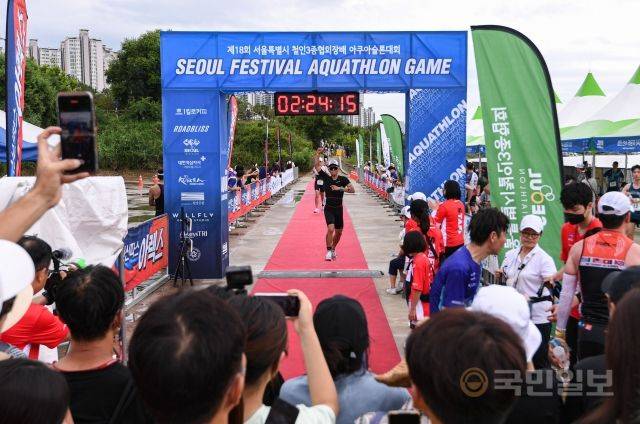 31일 서울 송파구 잠실 한강공원 수중보 일대에서 열린 제18회 서울특별시 철인3종협회장기 아쿠아슬론대회에서 참가자들이 결승선을 통과하고 있다.