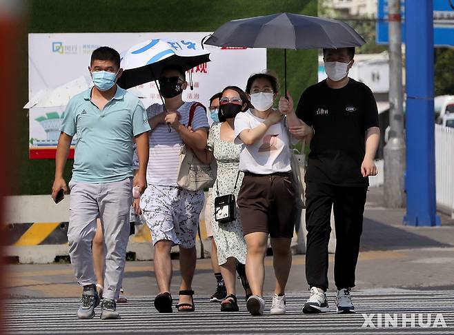 [상하이=신화/뉴시스] 지난 10일 중국 상하이 도심에서 주민들이 고온에 마스크를 착용하고 오가고 있다. 2022.07.13