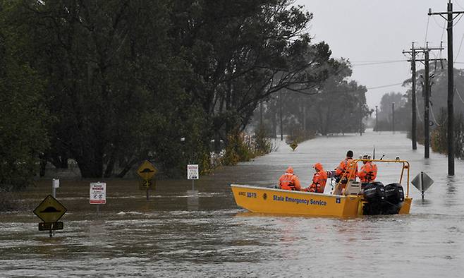 지난 7월 4일(현지시간) 호주 뉴사우스웨일스주 윈저의 호크스베리강이 범람하면서 도로가 물에 잠기자 구조대원들이 구조 보트를 타고 구조 활동에 나서고 있다. AP연합뉴스