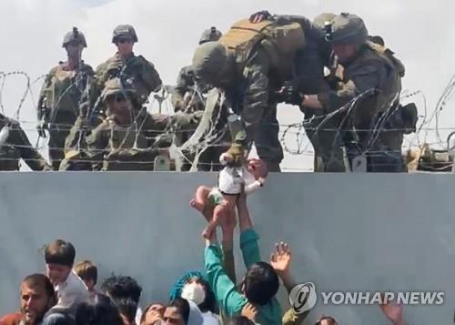 카불 공항 철조망 너머로 아기 건네는 아프간인  [로이터=연합뉴스]