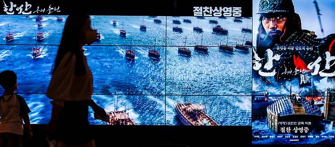 영화 '한산: 용의 출현'이 개봉 4일째인 30일 누적 관객 수 100만 명을 넘어서 흥행을 이어가고 있는 7월 31일 오전 서울시내 영화관을 찾은 시민들이 광고판 앞을 지나가고 있다.  /뉴시스