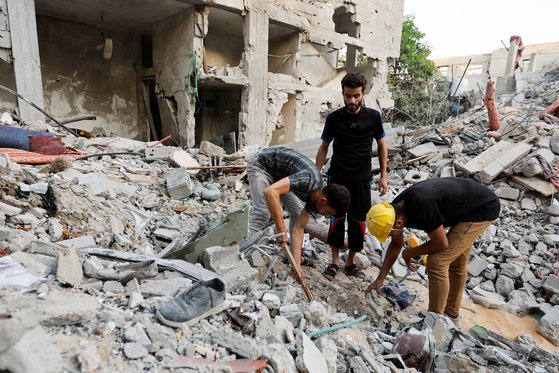 팔레스타인인들이 7일 이스라엘 폭격으로 파괴된 건물 잔해를 정리하고 있다. 로이터=연합뉴스