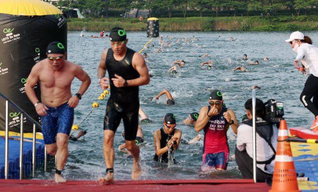 7일 오전 서울 송파구 롯데월드타워 일대에서 열린 아쿠아슬론 대회인 Oe RACE에 출전한 참가자들이 석촌호수에서 수영하고 있다. 이한결 기자
