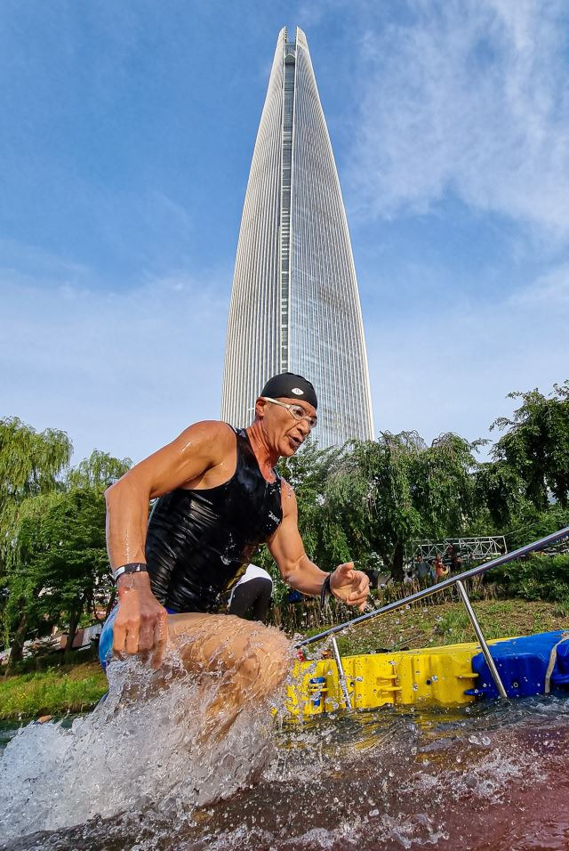 7일 오전 서울 송파구 롯데월드타워 일대에서 열린 아쿠아슬론 대회인 Oe RACE에 출전한 참가자들이 석촌호수에서 수영하고 있다. 이한결 기자