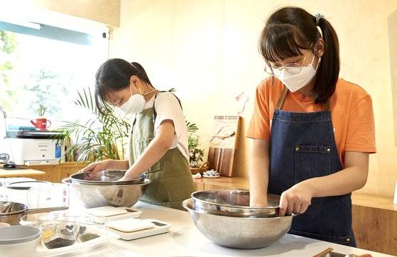 습식찹쌀가루를 체에 걸러 큰 볼에 담고 있는 박시오(왼쪽)·나예현 학생기자. 구움찰떡에는 떡처럼 쫄깃한 식감을 위해 습식찹쌀가루를 사용한다.