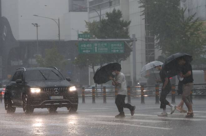 서울을 비롯한 중부지방에 호우특보가 내리며 많은 비가 내리고 있는 8일 서울 강남구 도산대로 횡단보도에서 우산을 쓴 시민들이 발걸음을 재촉하고 있다. /뉴스1