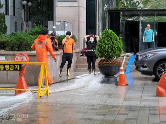 9일 오후 서울 강남역 인근 한 고층건물에서 펌프 호스로 물을 빼내던 한 소방대원이 힘이 부치는 듯 머리를 감싸쥐고 하늘을 바라보고 있다. 김재현 기자