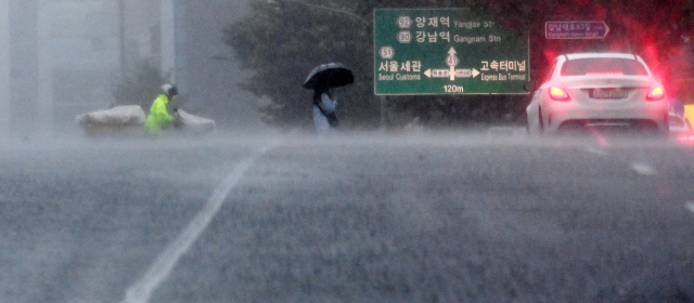 폭우가 내린 8일 서울 강남의 한 횡단보도에서 시민들이 우산을 쓰고 오가고 있다. 성형주 기자