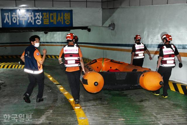 119 특수구조대원들이 10일 주황색 소방 구명보트를 들고 폭우로 휩쓸린 실종자들을 찾기 위해 서울 강남역 인근 강남빌딩 지하주차장 입구로 들어가고 있다. 배우한 기자