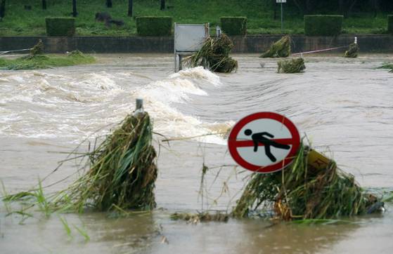 A roadsign near a stream in Cheongju, North Chungcheong, falls over as torrents caused by rainfall continued Thursday. [YONHAP]