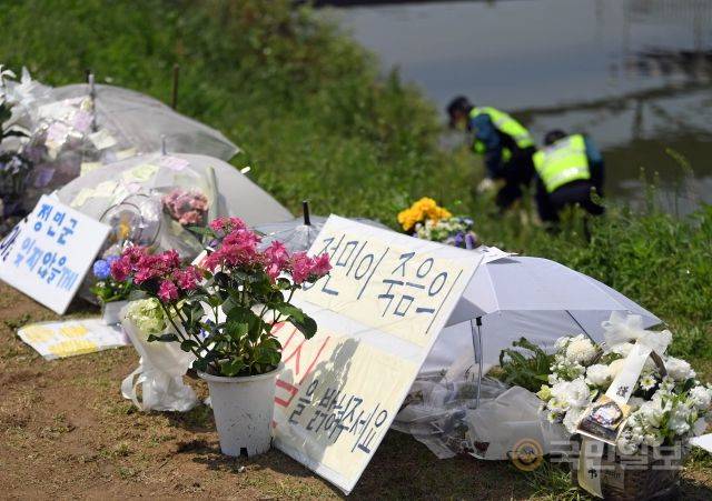 지난해 5월 18일 서울 반포한강공원 수상택시 승강장 인근에 고 손정민씨의 추모공간이 마련돼있다. 추모공간 너머 손씨 친구 휴대전화 등을 수색하고 있는 경찰의 모습이 보인다. 윤성호 기자