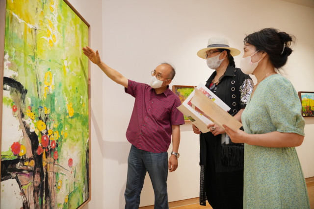 ▲강해중(왼쪽 첫 번째) 작가가 BNK경남은행갤러리를 찾은 관람객들에게 작품을 안내하고 있다.ⓒ BNK경남은행
