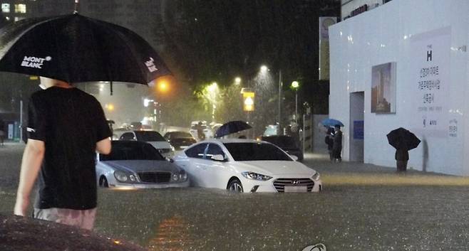 지난 8일 밤 서울 강남구 대치동 은마 아파트 부근 도로와 인도가 물에 잠기면서 차량과 보행자가 통행에 불편을 겪고 있다. 연합뉴스