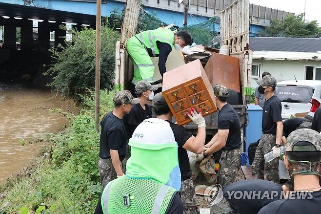 송파 화훼마을 수해복구 총력 (서울=연합뉴스) 김주성 기자 = 11일 오전 대규모 수해를 입은 서울 송파구 화훼마을에서 육군 52사단과 56사단 장병들이 환경미화원들과 함께 비에 젖어 못 쓰게 된 물건들을 정리하고 있다.  2022.8.11 utzza@yna.co.kr
