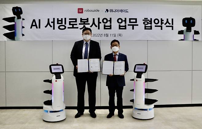 위니아에이드가 자율주행 서비스 로봇 전문업체 ‘로보와이드’와 업무 협약을 체결했다.  (왼쪽부터) 길진형 로보와이드 상무이사, 정창규 위니아에이드 상무./ 위니아 제공