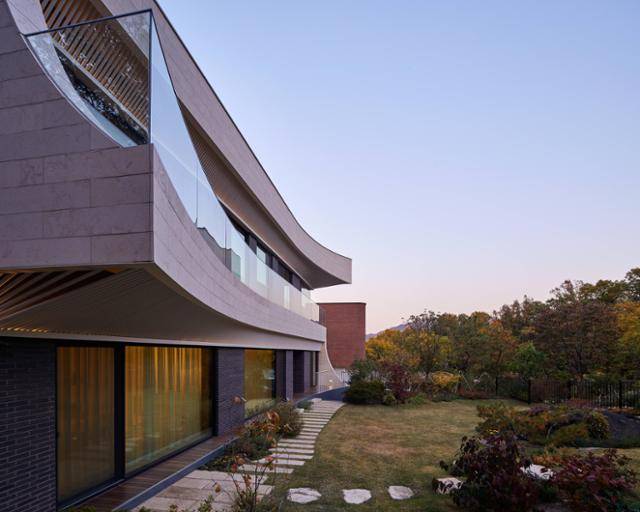 터를 닦을 때 나온 바위는 그대로 무심히 놓였고 주변 수목을 최대한 끌여들인 조경으로 여유로운 분위기를 연출했다. 집의 동쪽으로 들린 처마에서 맞은편 청계산의 능선이 연결된다. 노경 건축사진작가 제공