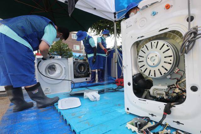 삼성전자 서비스센터 직원들이 11일 오후 서울 관악구 남부초등학교에 마련된 침수피해주민 가전제품 무료수리 서비스 부스에서 가전제품을 수리하고 있다. 무상수리팀에는 삼성전자, LG전자, 위니아·위니아에이드 가전 3사가 참여했다. 뉴스1