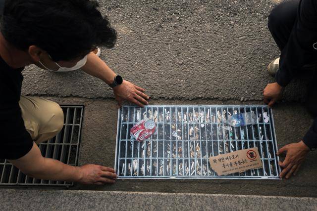 12일 서울 강남구청 앞에서 이제석광고연구소가 진행한 캠페인. 도로변 하수도와 똑같은 모양으로 제작된 스티커 하수도가 담배꽁초와 쓰레기로 막혀 있다. 뉴스1