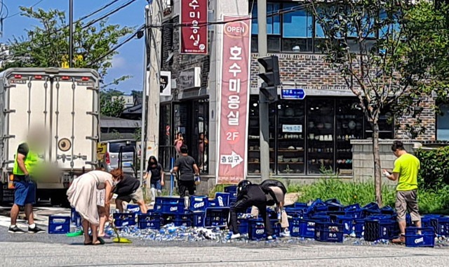 ▲ 강원 춘천 동면 만천호에서 수십 개의 맥주 박스가 도로에 쏟아지자 시민들이 함께 치우고 있다 [연합뉴스 독자제공]