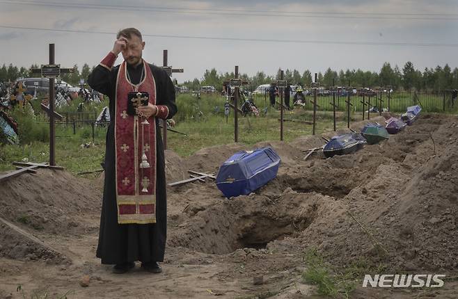 [부차=AP/뉴시스] 11일(현지시간) 우크라이나 키이우 외곽 부차에서 러시아군에 의해 살해된 신원 미상의 민간인에 대한 장례식에서 사제가 기도를 하고 있다. 2022.08.12.