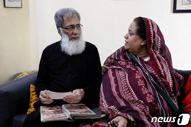 알리 하반 바카이가 파키스탄 카라치에 있는 자택에서 아내와 얘기를 나누면서 가족 사진을 보고 있다. ⓒ 로이터=뉴스1