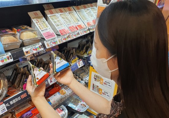 한 고객이 이마트24 매장에서 중량을 50% 늘린 '더빅 삼각김밥'을 살펴보고 있다. / 이마트24 제공