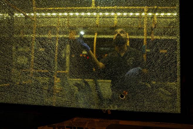 14일 예루살렘 구시가지에서 버스 총기 난사 사건이 일어난 뒤 이스라엘 보안 당국 관계자가 부서진 버스 유리창을 살펴보고 있다. 로이터 연합뉴스