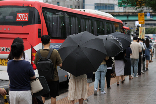 기록적 폭우가 지나가고도 비가 계속되던 지난 9일 오전 직장들이 서울 동작구 사당역 인근 정류장에서 버스를 타고 있다. 연합뉴스